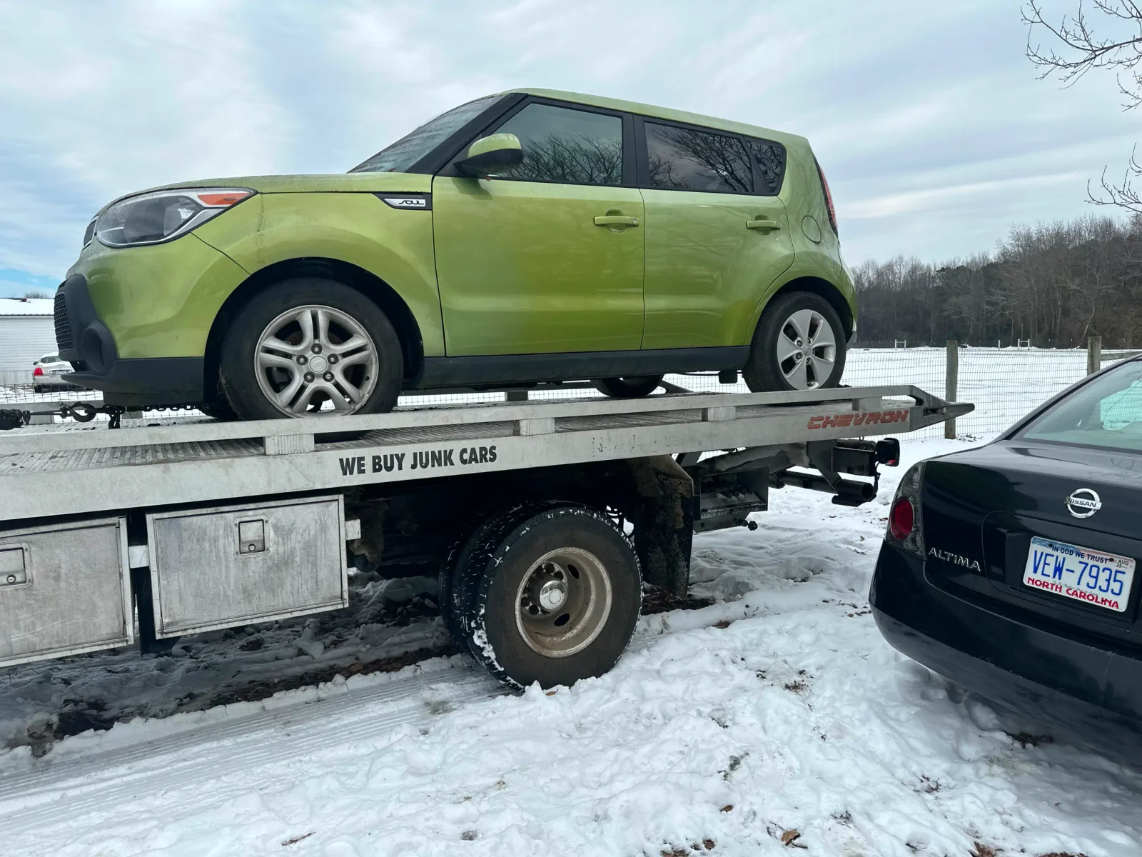 Green compact vehicle on a flatbed in snowy conditions