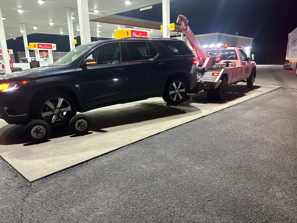 Nano’s pink wrecker lifting a dark minivan at night