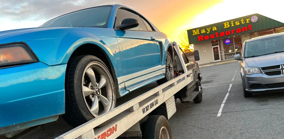 Blue car secured on a flatbed tow truck